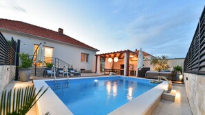 Una piscina con pérgola y zona de estar al aire libre.
