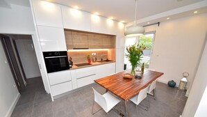 Una cocina moderna con armarios blancos, encimera de madera y una mesa con sillas.