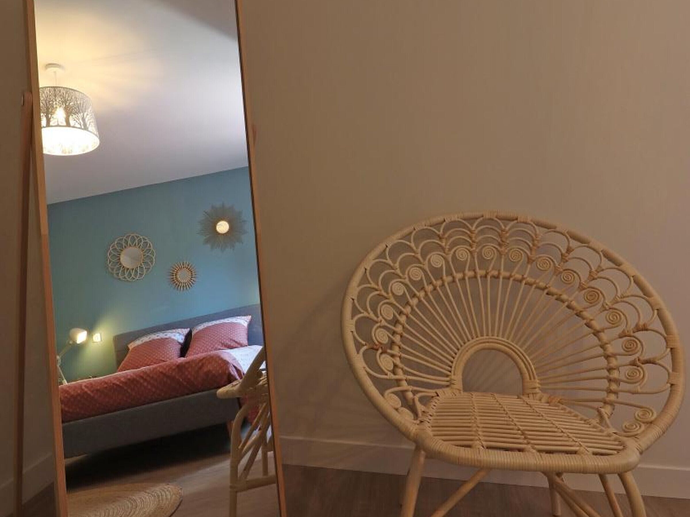 A room with a bed, a wicker chair, and decorative wall art.