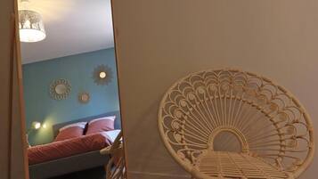 A room with a bed, a wicker chair, and decorative wall art.