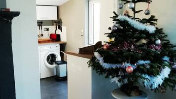 A modern kitchen with a washing machine, a dining area with a small table, and a Christmas tree.