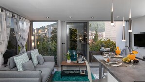 Una sala de estar moderna con un sofá gris, una mesa de centro y un comedor con televisor y espacio para desayunar.