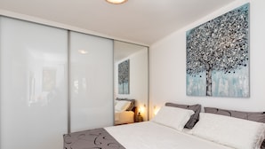 Un dormitorio con cama, un espejo grande y un cuadro de un árbol.