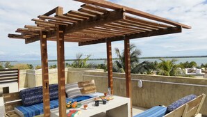 Une pergola en bois avec une table et des bancs, donnant sur une étendue d’eau.