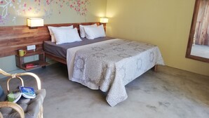 Une chambre à coucher comprenant un lit, des lampes de chevet, une table de chevet, une chaise et un mur orné d’une fresque florale.