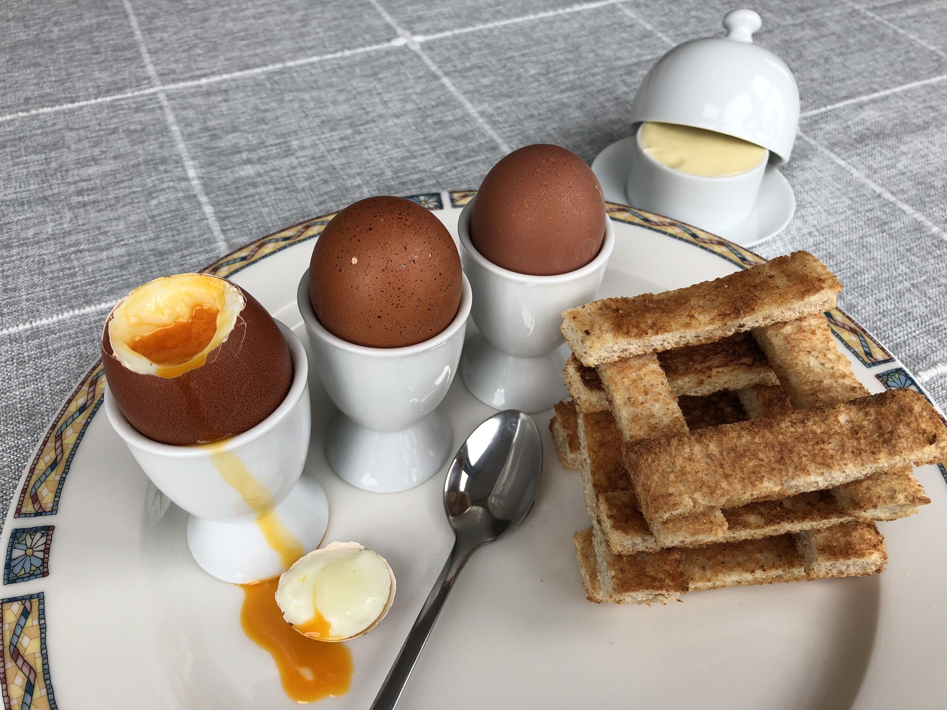 A plate with three custard cups, a stack of bread, and a spoon.