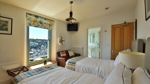 A hotel room with two beds, a view of the city, a television, and a wooden door. - Beacon House (Brixham)