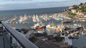 A harbor with numerous boats docked, a clear sky, and buildings on a hillside in the background. - Beacon House (Brixham)