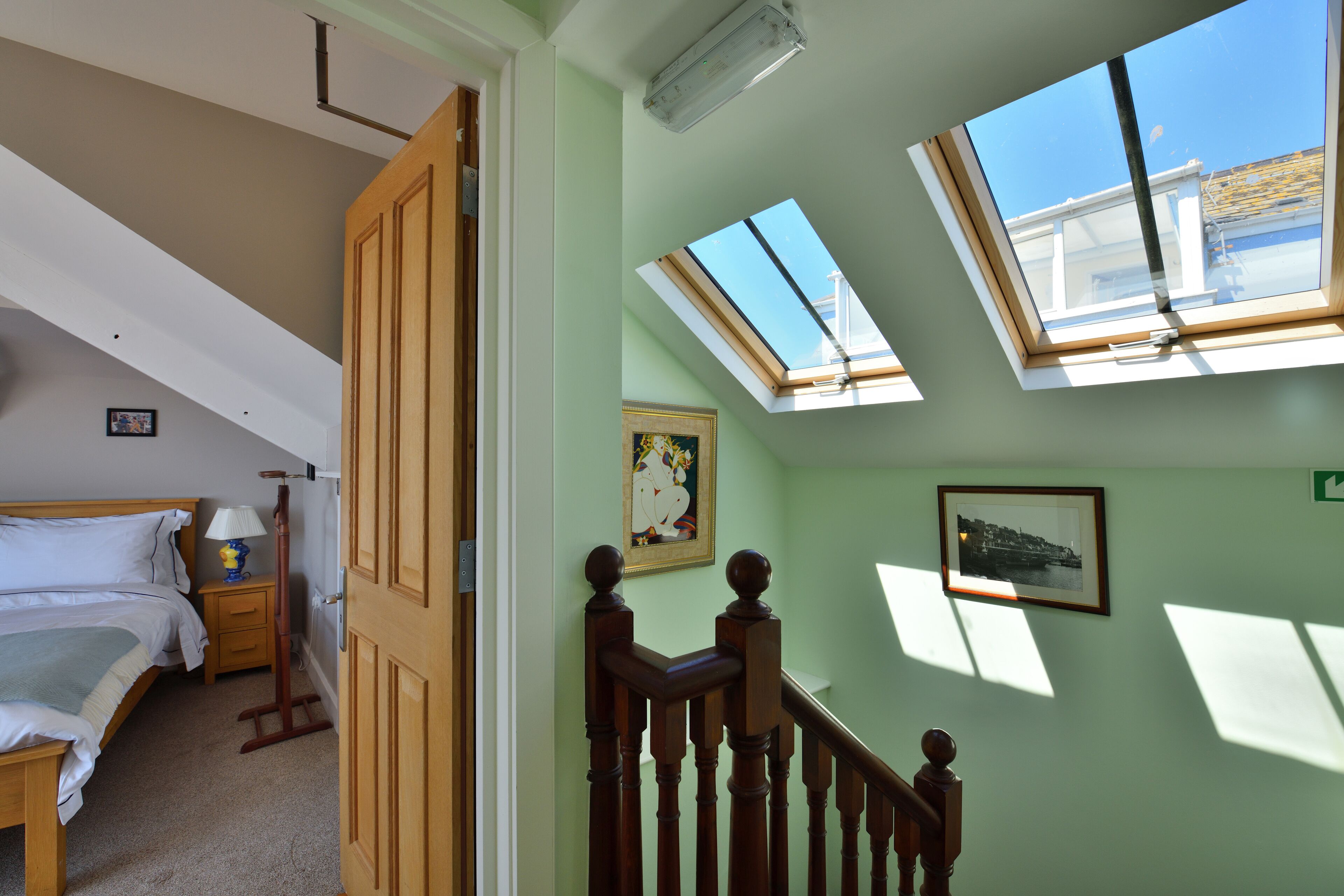 A bedroom with a bed, bedside table, lamp, and a skylight.