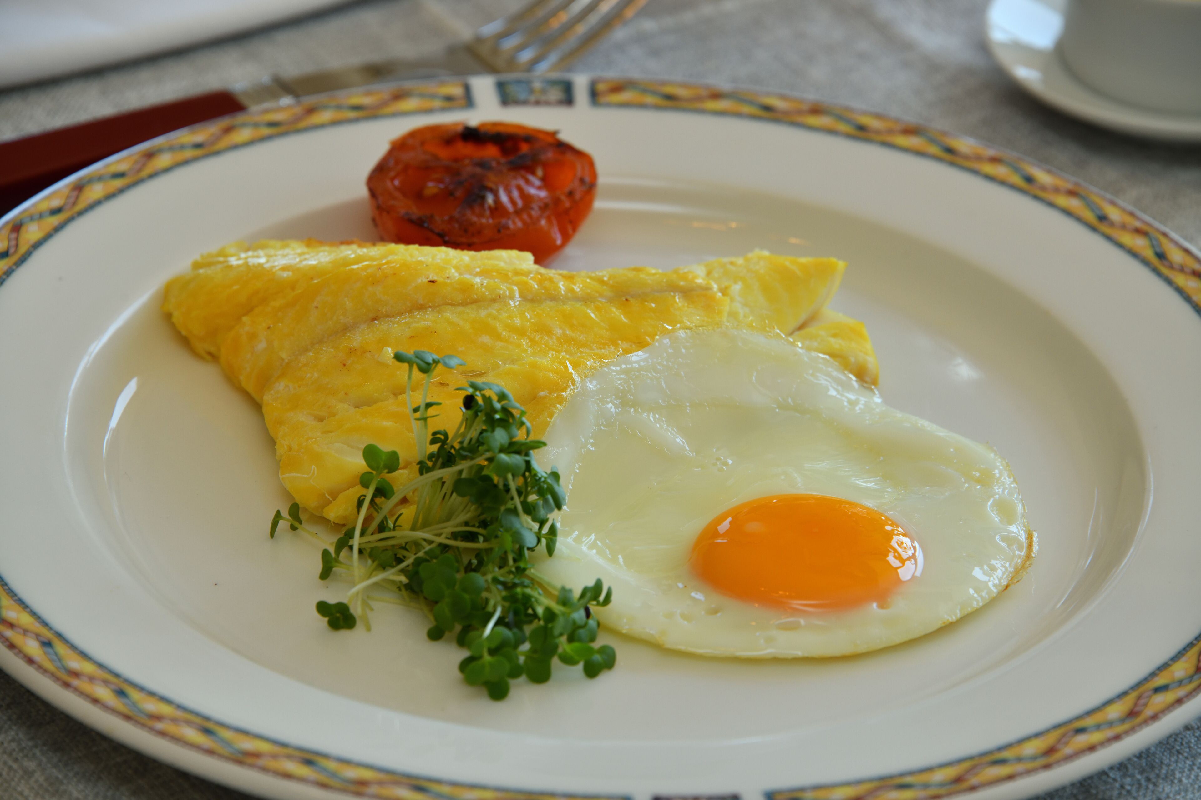 A plate with an omelette, a fried egg, and a grilled tomato.