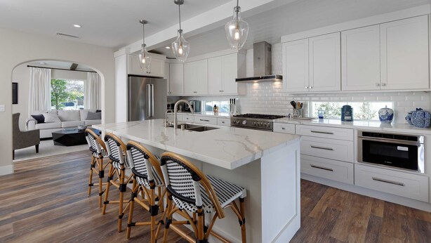 A modern kitchen with white cabinetry, a marble island, and a dining area with wicker chairs. - Gorgeous Designer Oasis in Pacific Beach, central AC, wifi, and parking! (San Diego)