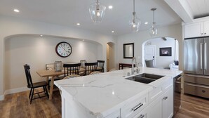 A modern kitchen with a marble island, stainless steel appliances, and pendant lighting. - Gorgeous Designer Oasis in Pacific Beach, central AC, wifi, and parking! (San Diego)