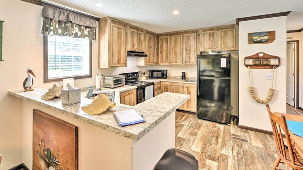 A kitchen with wooden cabinets, a refrigerator, a microwave, and a stove. - 'Pelican Place' Coastal Cottage Walk to Back Sound (Harkers Island)