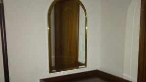 A room with a wooden cabinet, a microwave, and a mirror on the wall. - Hotel Leppiner Hof (Arendsee)