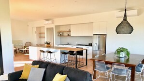 A modern kitchen with white cabinets, a stainless steel refrigerator, and a hanging pendant light. - Sea Salt Beach House | Luxury Coastal Escape for 12 (Goolwa Beach)
