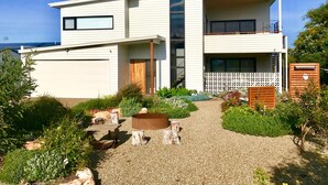 A modern two-story house with a covered patio, a fire pit, and a view of the ocean. - Sea Salt Beach House | Luxury Coastal Escape for 12 (Goolwa Beach)