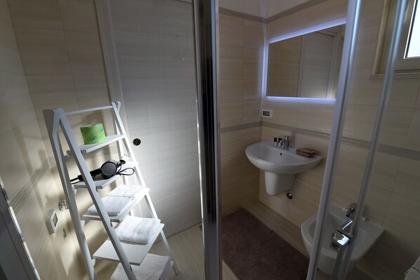A bathroom with a white sink, mirror, and a towel rack with towels.