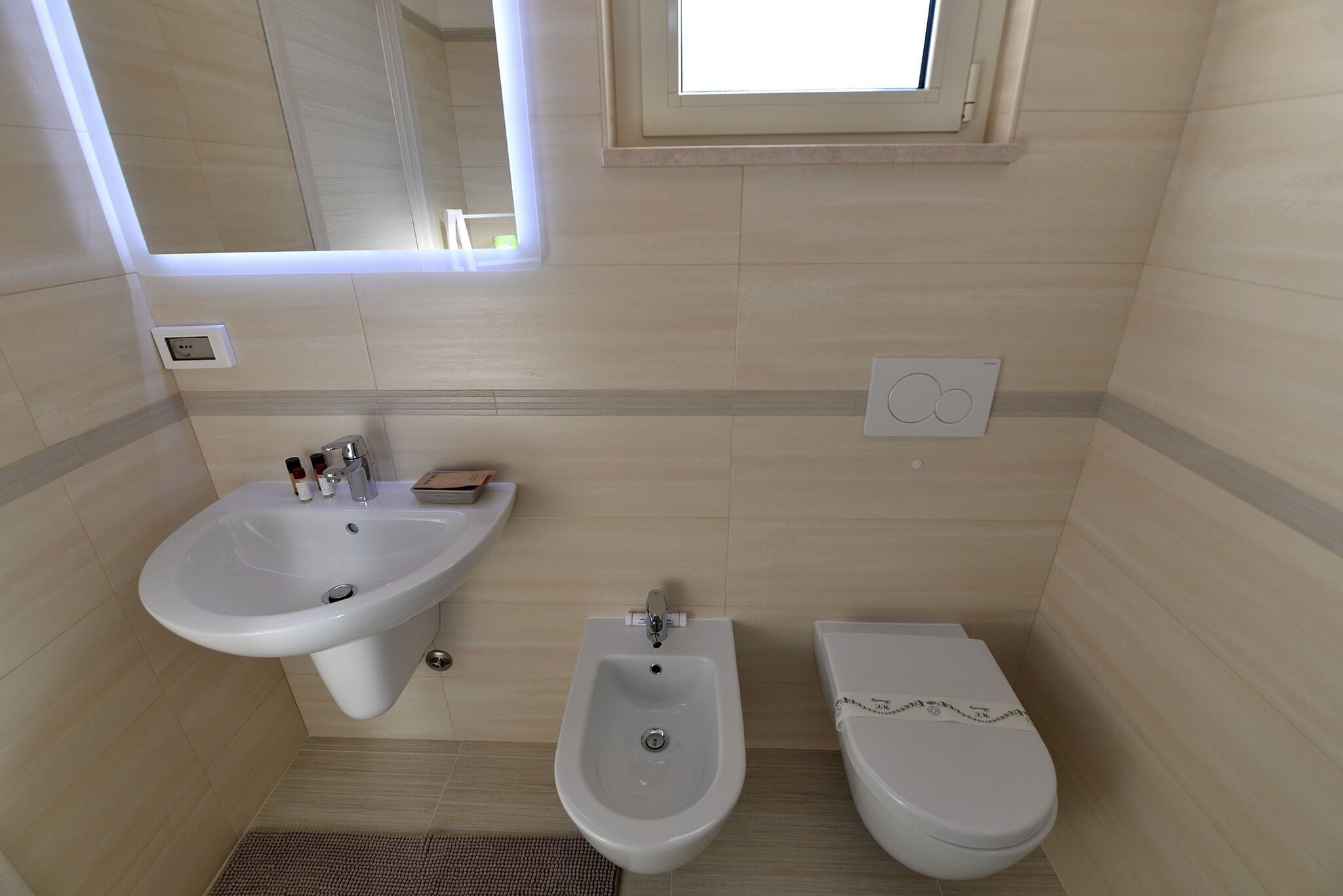 Ein Badezimmer mit einem Standwaschbecken, einem Bidet und einer Toilette.