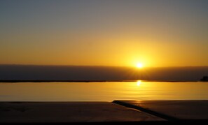 Ein Sonnenuntergang über ruhigem Wasser, mit einem hölzernen Steg, der sich ins Wasser erstreckt.
