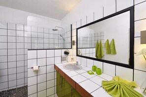 Ein modernes Badezimmer mit einem weißen Waschbecken, grünen Handtüchern und einem großen Spiegel.