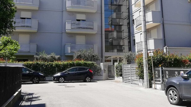 A multi-story residential building with balconies, a gated entrance, and parked cars. - Sea House Rimini Fiera (Rimini)