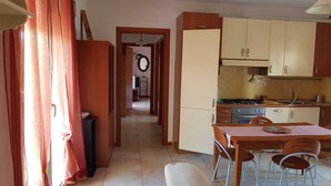 A compact kitchen with wooden cabinets and a dining area with a table and chairs. - Sea House Rimini Fiera (Rimini)
