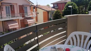 A balcony with a table and chairs, a view of neighboring houses, and a clear sky. - Sea House Rimini Fiera (Rimini)