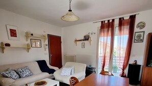A living room with a sofa, coffee table, dining table with chairs, and a kitchen area. - Sea House Rimini Fiera (Rimini)