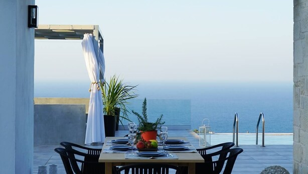 Un coin repas avec une table dressée pour deux personnes, offrant une vue sur la côte.