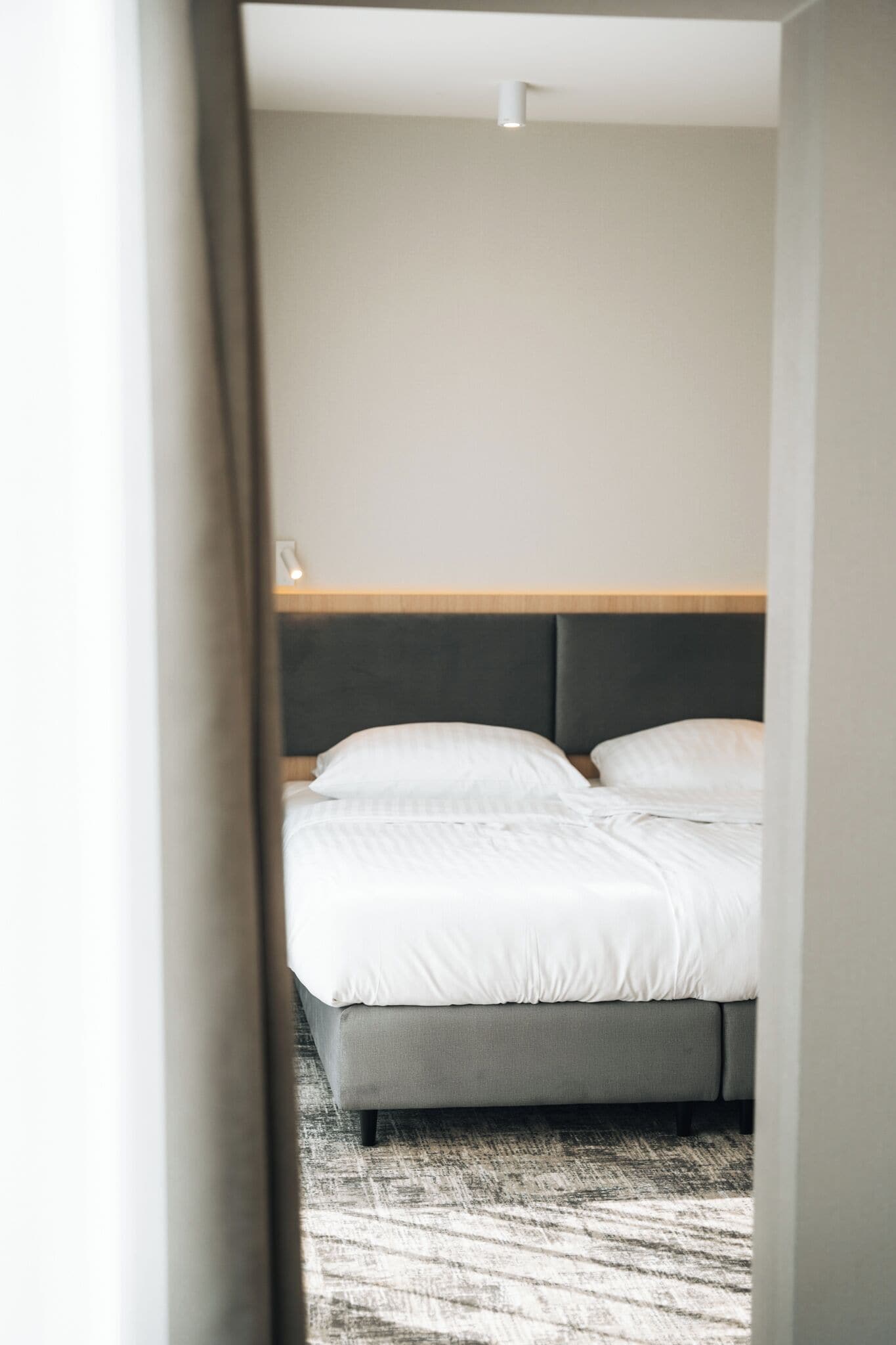 Una habitación de hotel con cama, cabecero y piso alfombrado.