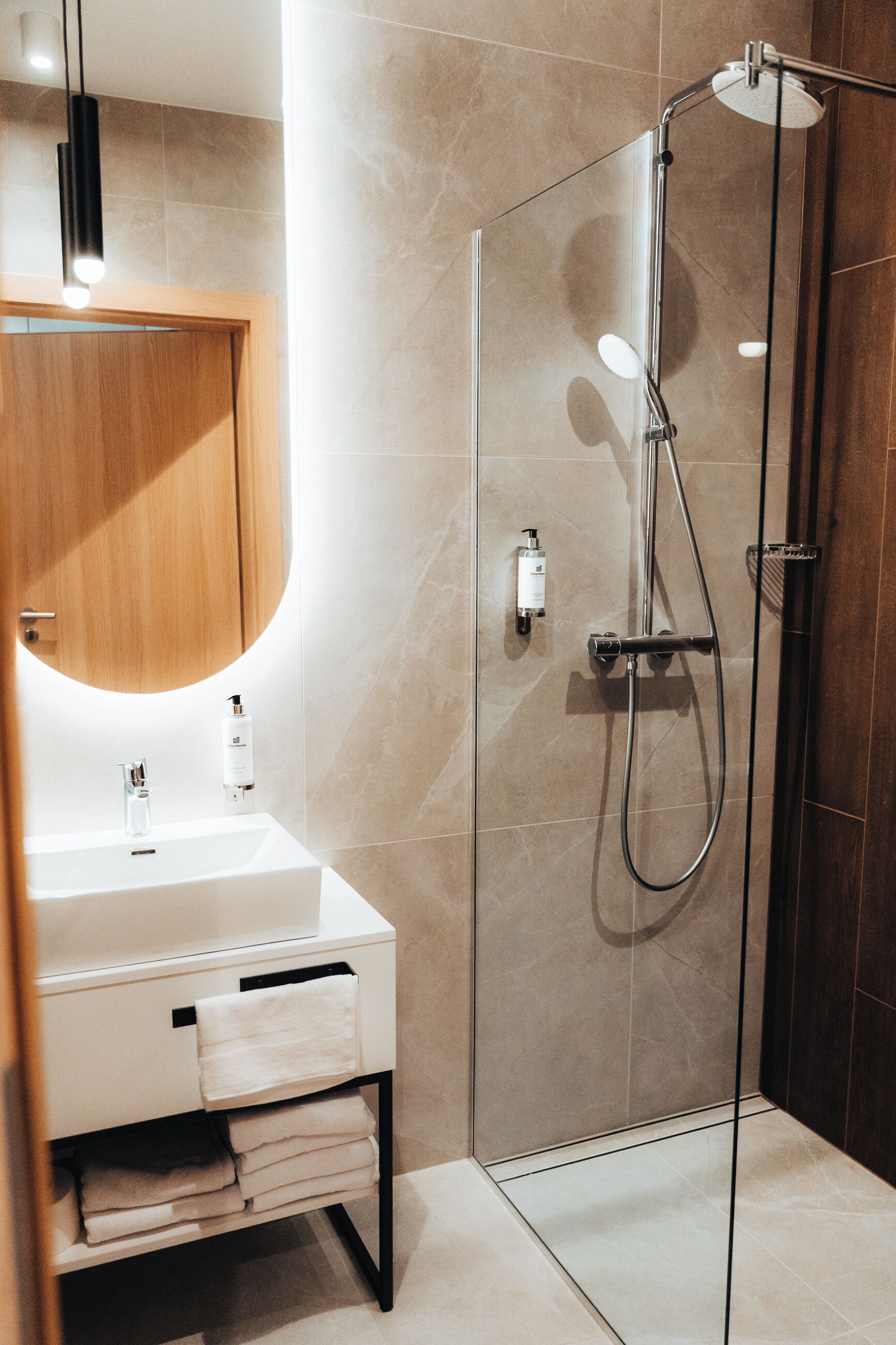 A modern bathroom with a glass-enclosed shower, a white sink, and a wooden cabinet with a mirror.