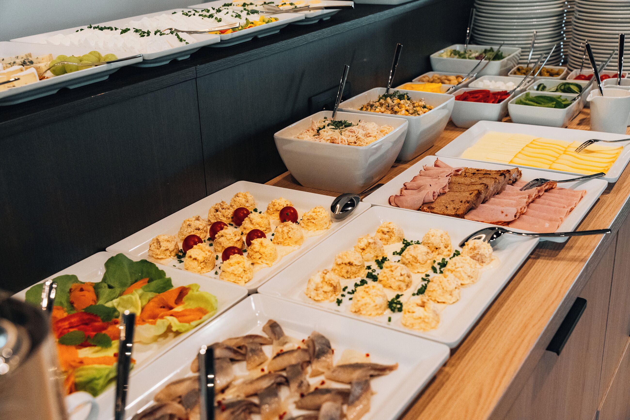 A buffet with various food options including salads, meats, and cheeses.