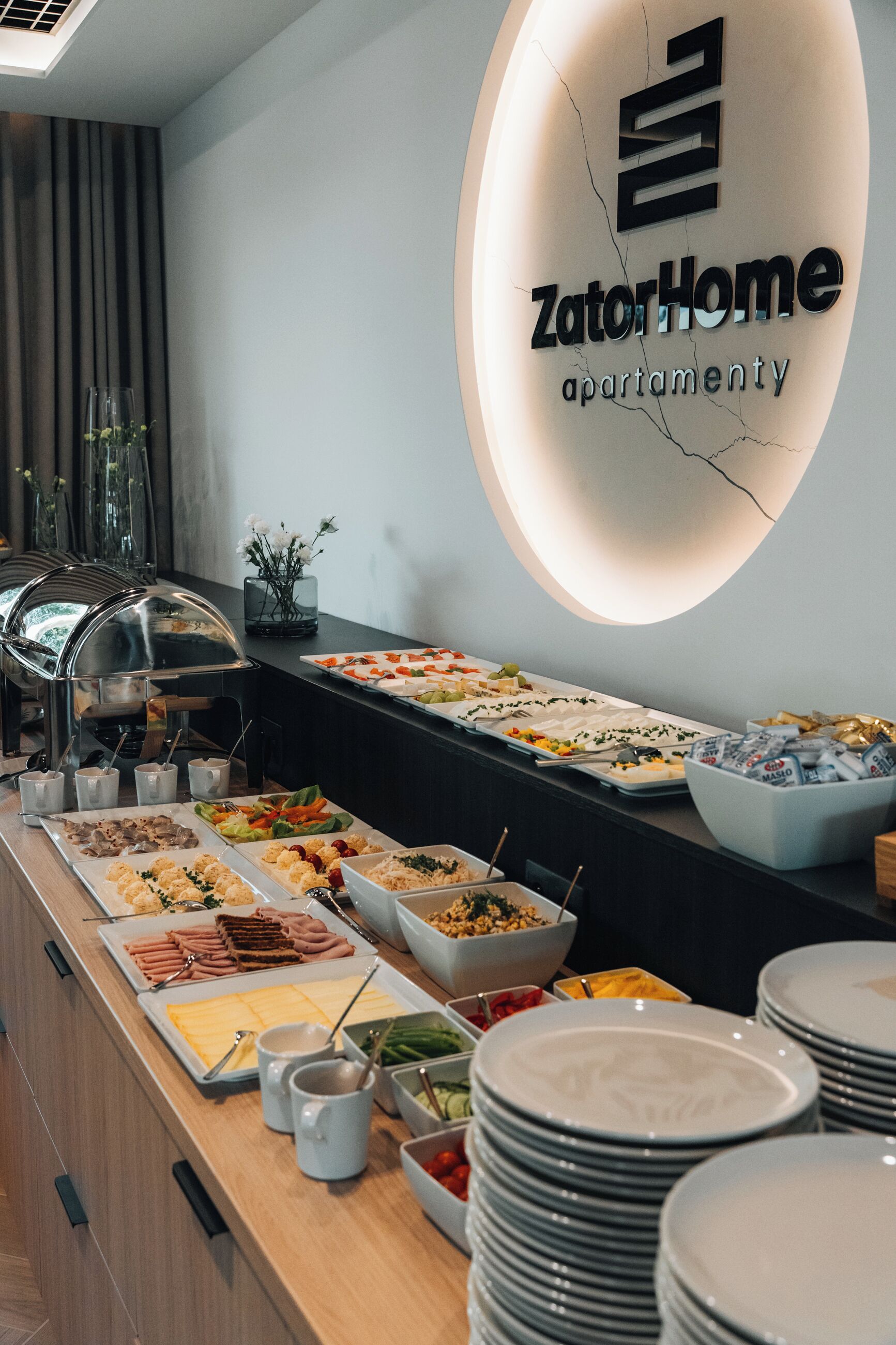 Montaje tipo bufé con diferentes opciones de comida y un cartel para apartamentos ZatorHome.