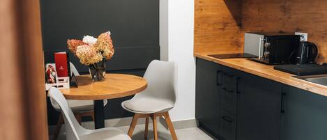 Eine moderne Küche mit einer Holzausziehtafel, einer Kaffeemaschine und einem Blumenstrauß auf dem Tisch.