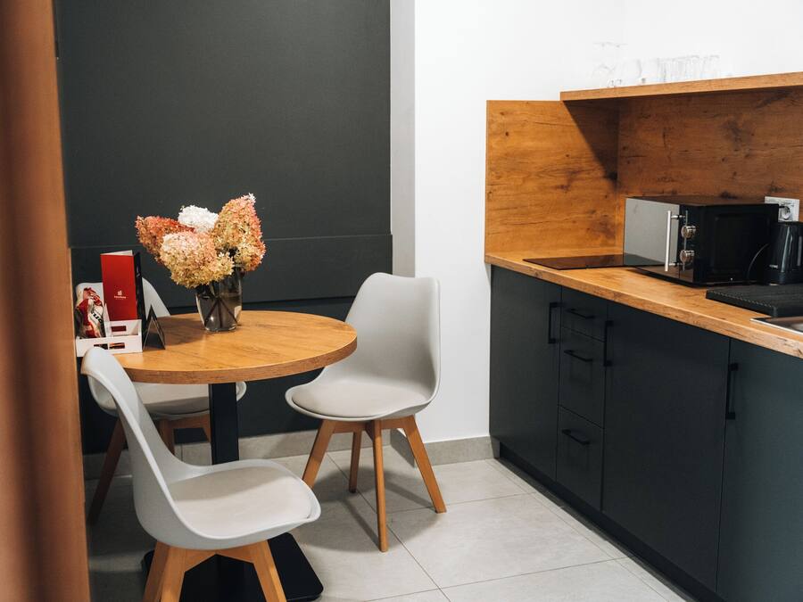 A modern kitchen with a wooden countertop, a coffee machine, and a vase of flowers on the table.