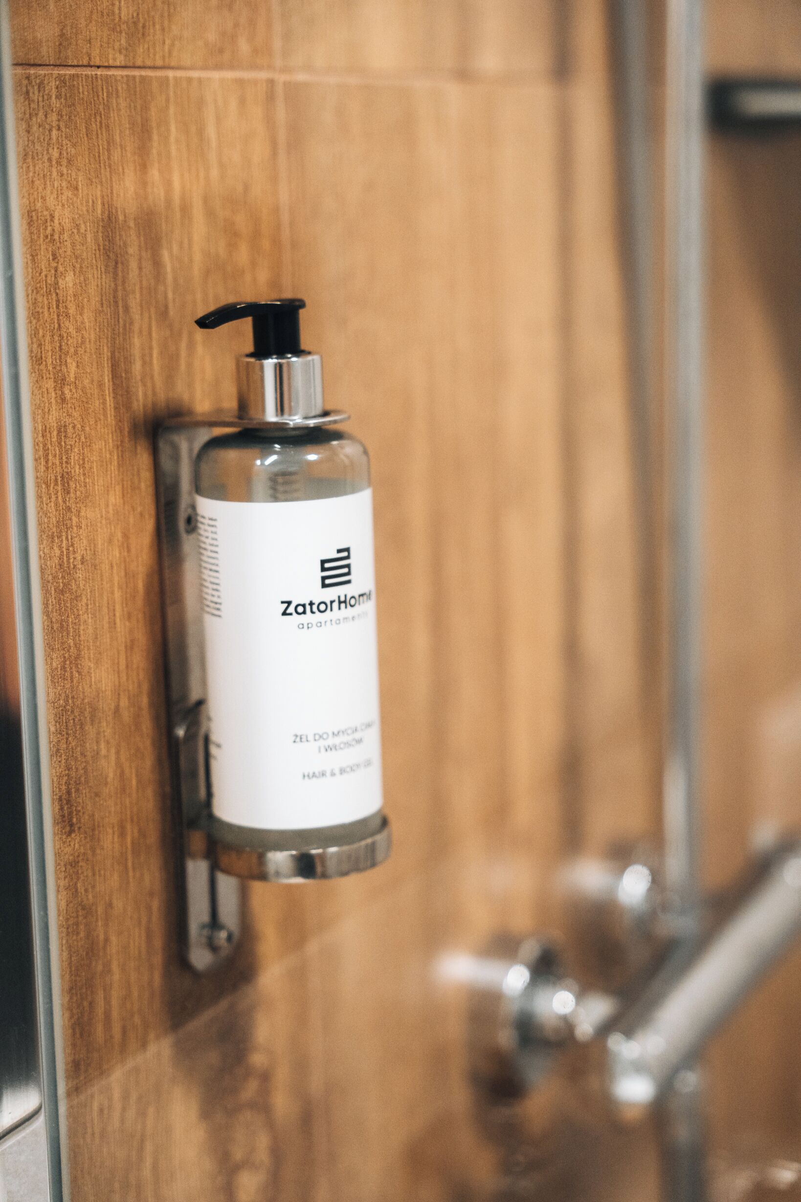A bathroom with a wooden door and a ZatorHome shampoo bottle mounted on it.