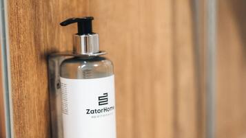 A bathroom with a wooden door and a ZatorHome shampoo bottle mounted on it.