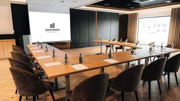 A conference room with a long table, chairs, and a projector screen displaying 'ZatorHome apartment'.