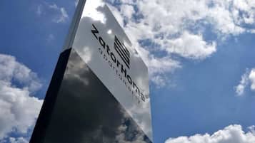 A tall, reflective glass structure with the text 'ZOTTO Home' and 'ZOTTO Hospitality' on it.