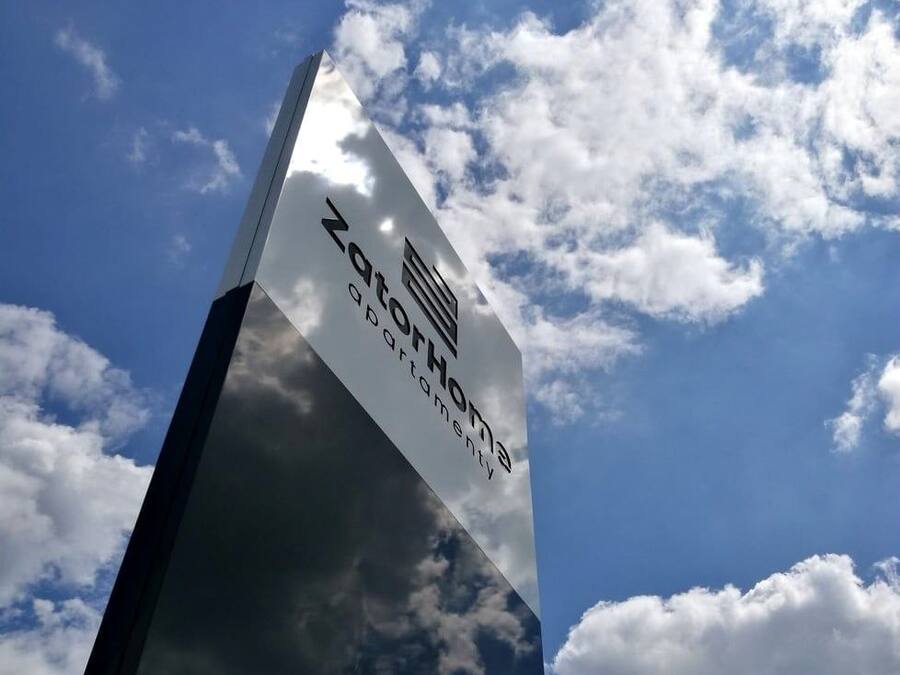 A tall, reflective glass structure with the text 'ZOTTO Home' and 'ZOTTO Hospitality' on it.