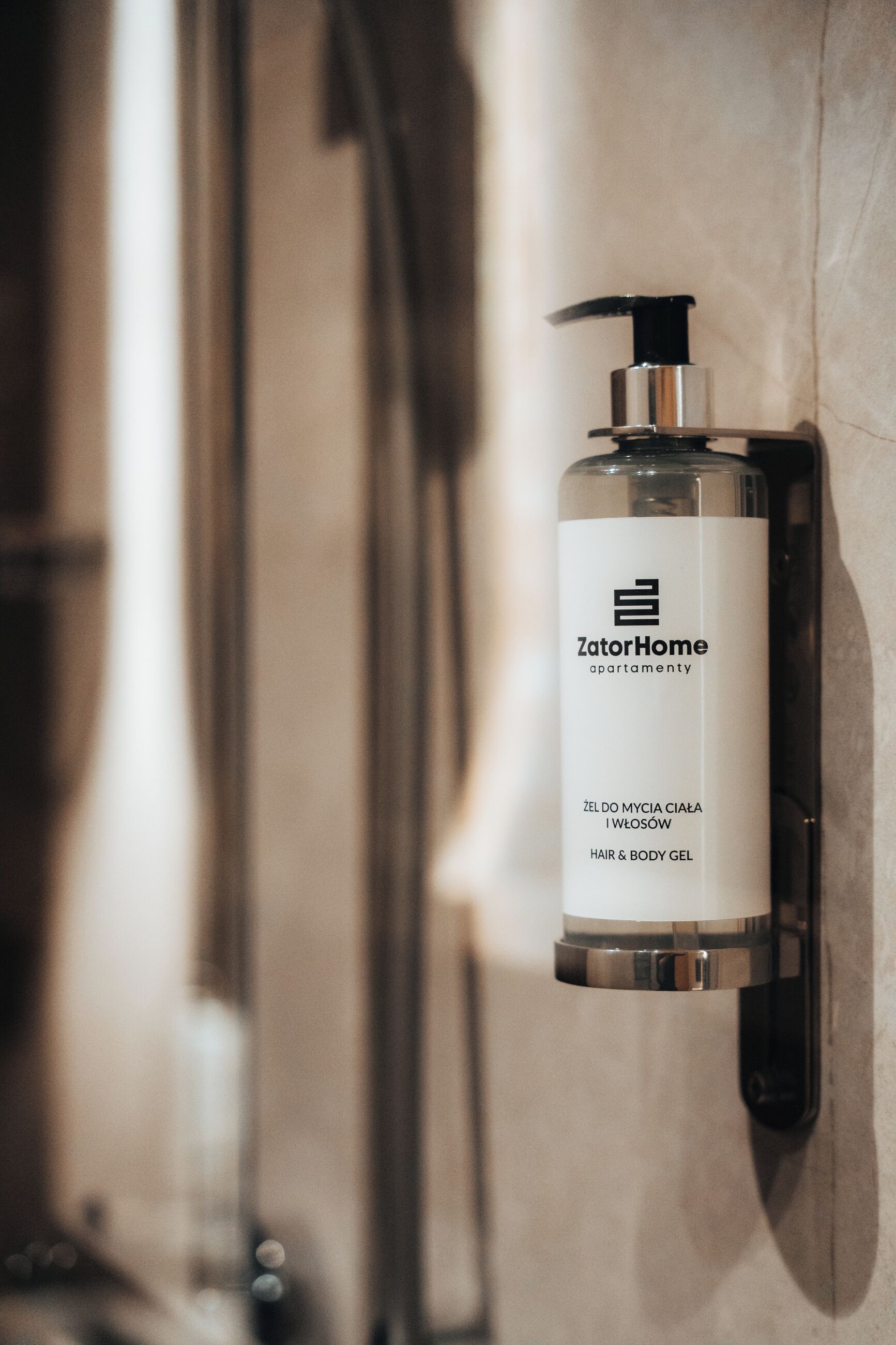 Une bouteille de gel pour cheveux et corps de la marque ZatorHome est fixée au mur dans une salle de bain.