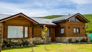 A wooden cabin with a stone foundation, large windows, and a sloped roof. - MOUNTAIN CABIN DREAM (San Carlos de Bariloche)