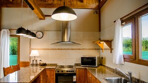 A kitchen with granite countertops, wooden cabinets, a stove, a microwave, and a sink. - MOUNTAIN CABIN DREAM (San Carlos de Bariloche)