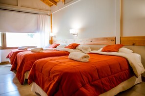 Ein Hotelzimmer mit zwei Betten, jeweils mit roter Bettwäsche und weißen Kissen, und einem hölzernen Kopfteil.