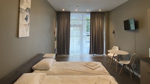 A hotel room with two beds, a desk, a chair, a TV, and a view of the outdoors. - Jurmala Park House (Jurmala)