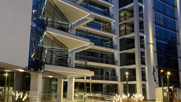 A modern multi-story building with a glass facade, outdoor seating area, and illuminated pathways. - Jurmala Park House (Jurmala)