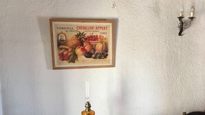 Ett träbord med en lampa, en inramad bild av frukt och en väggmonterad lampa.