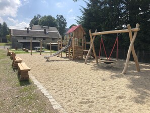 Children can play on the slide, swings, and climbing frame in this outdoor play area.