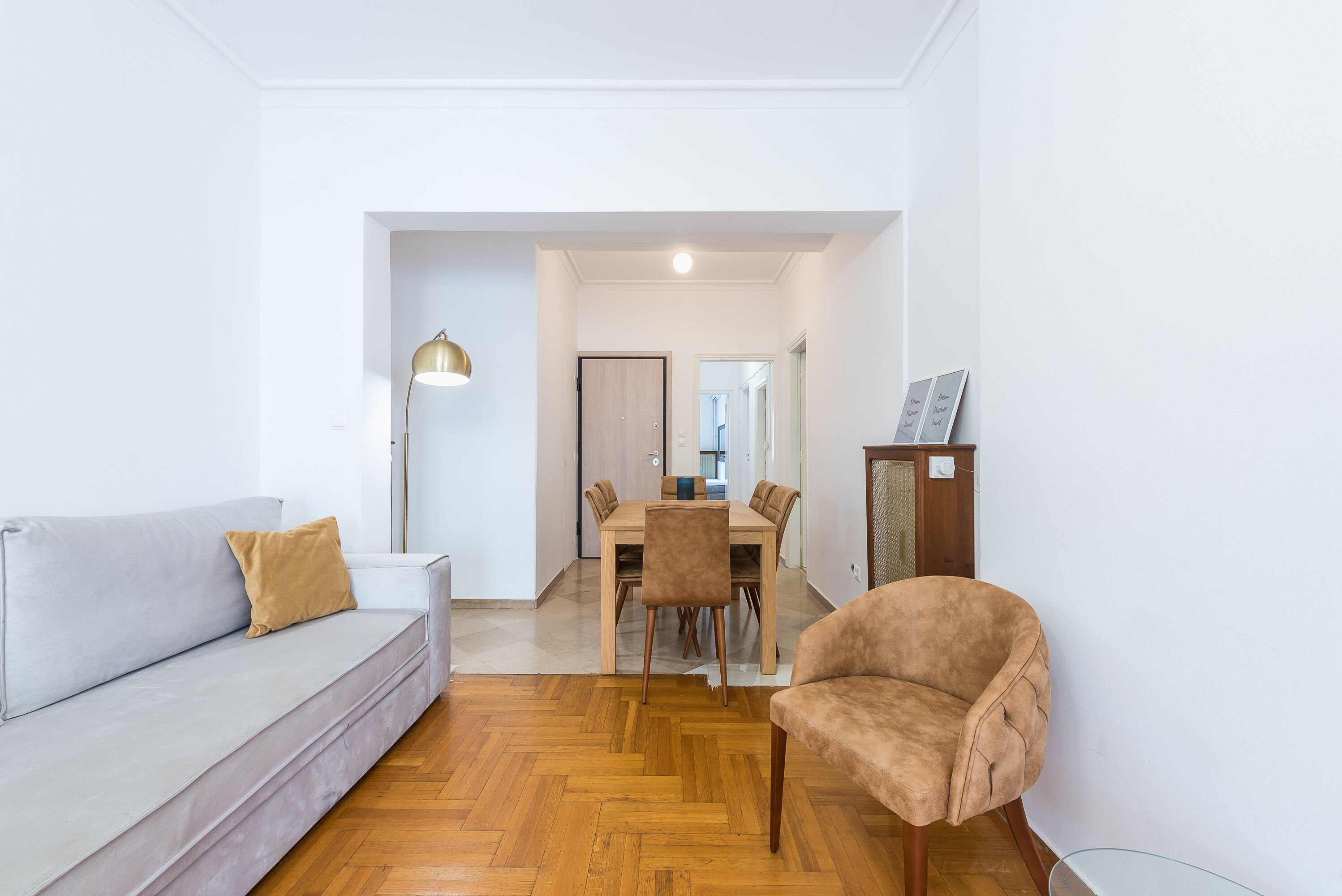 A modern living room with a sofa, a chair, a dining table, and a lamp.
