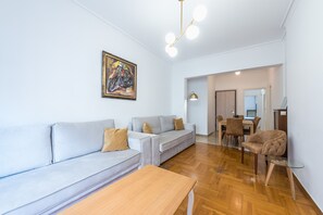 A modern living room with a sofa, a coffee table, and a dining area with a table and chairs.